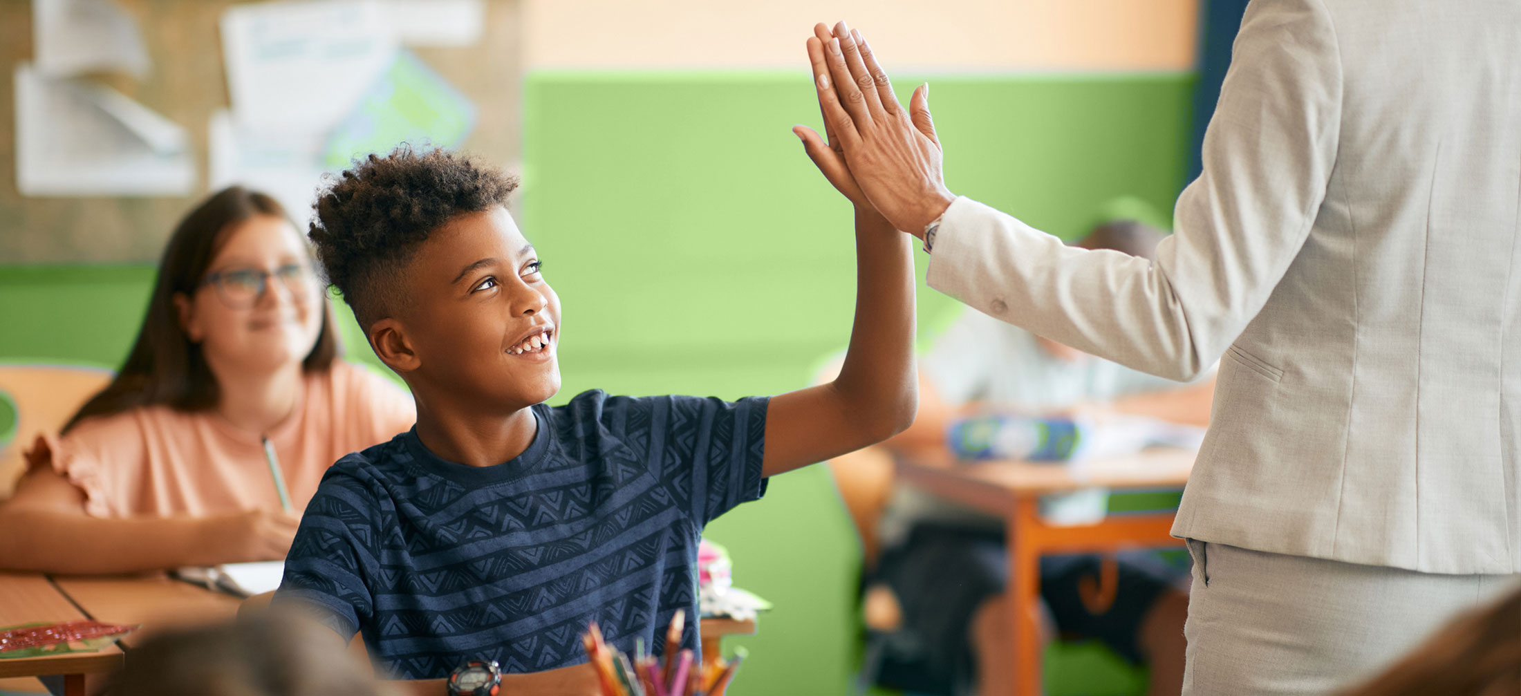 Middle School age student high-fiving their teacher.
