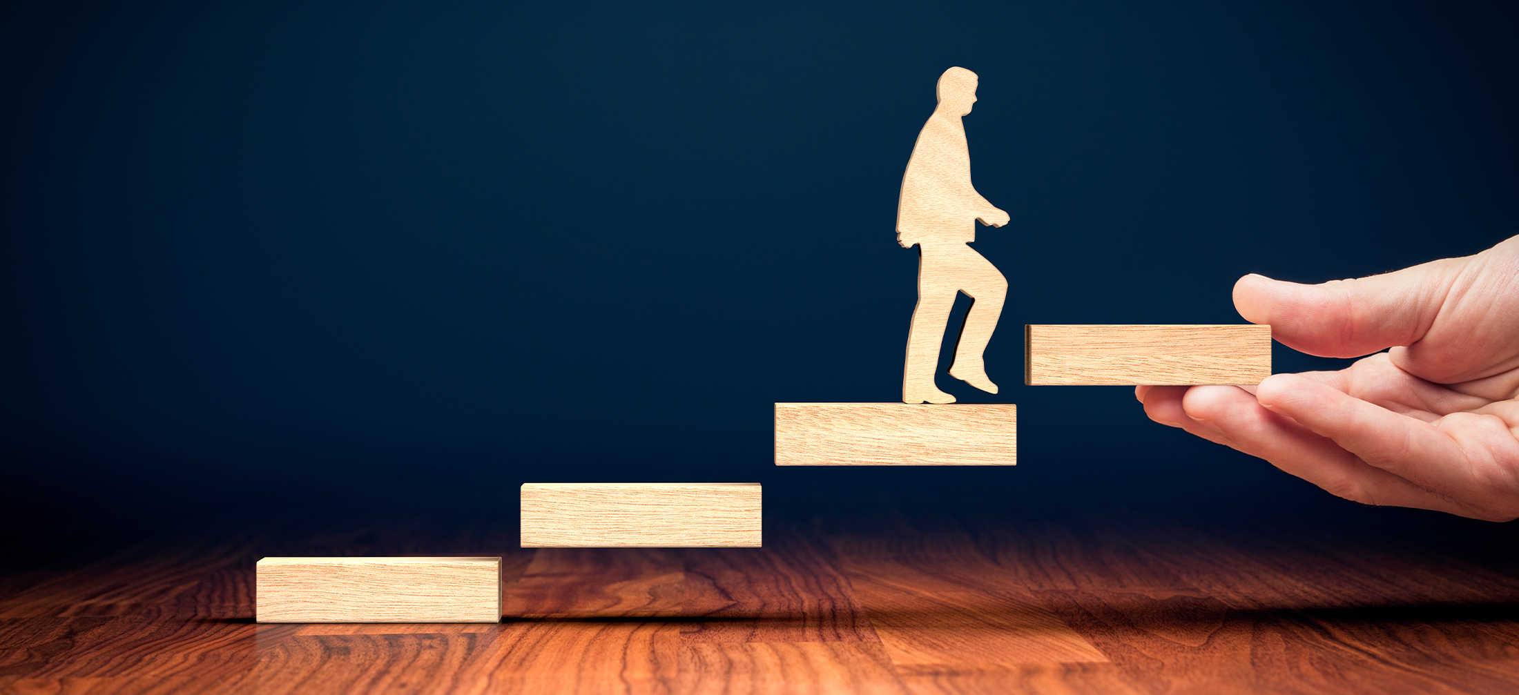 image of a person walking up wooden steps that are being added by a large hand, one at a time.