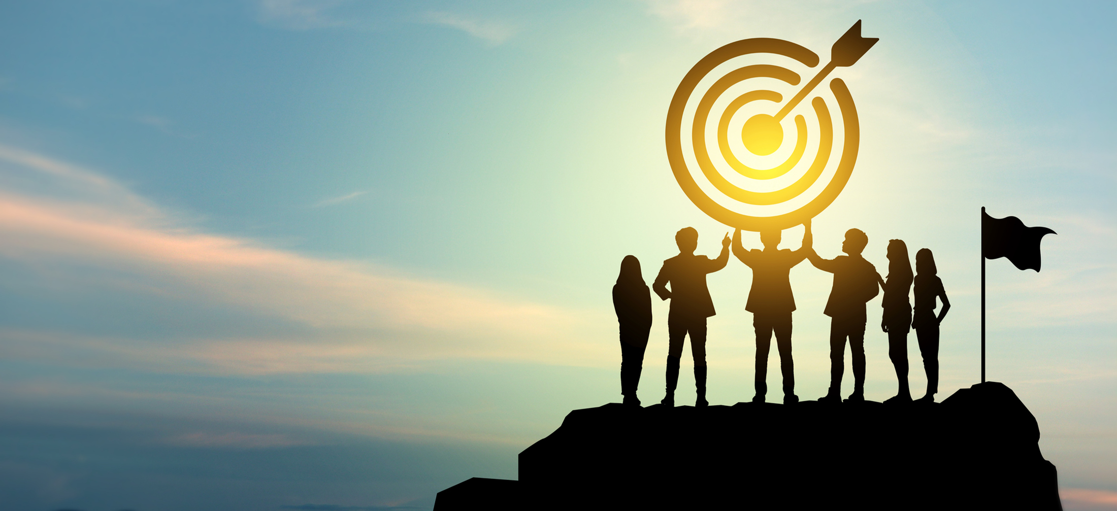 Image of a team standing on top of a hill holding a target over their heads