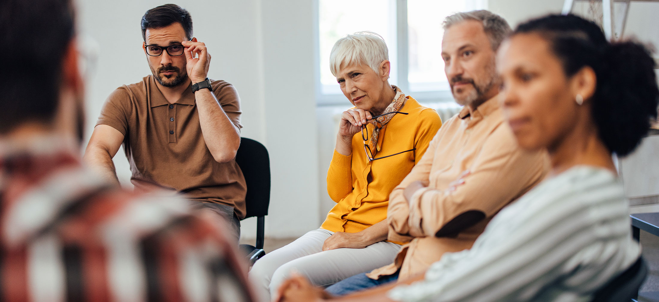 Group of adults sitting in a circle and talking about something.