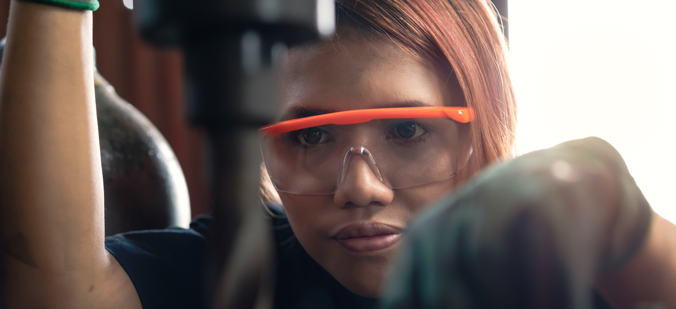 Student wearing orange safety glasses, learns to use a drill press
