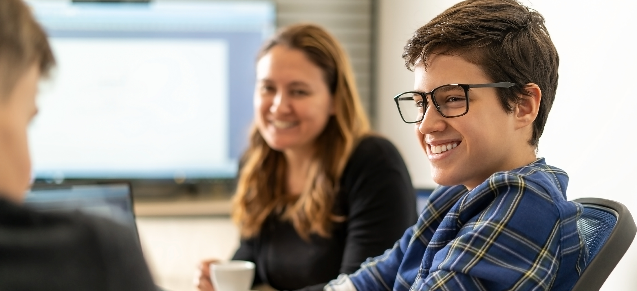 Smiling intern with the glasses talking to colleagues in the office.Positive atmosphere in the office with young interns and with a supervisor
