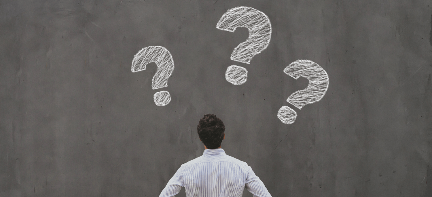 man looking at question marks on chalkboard better questions