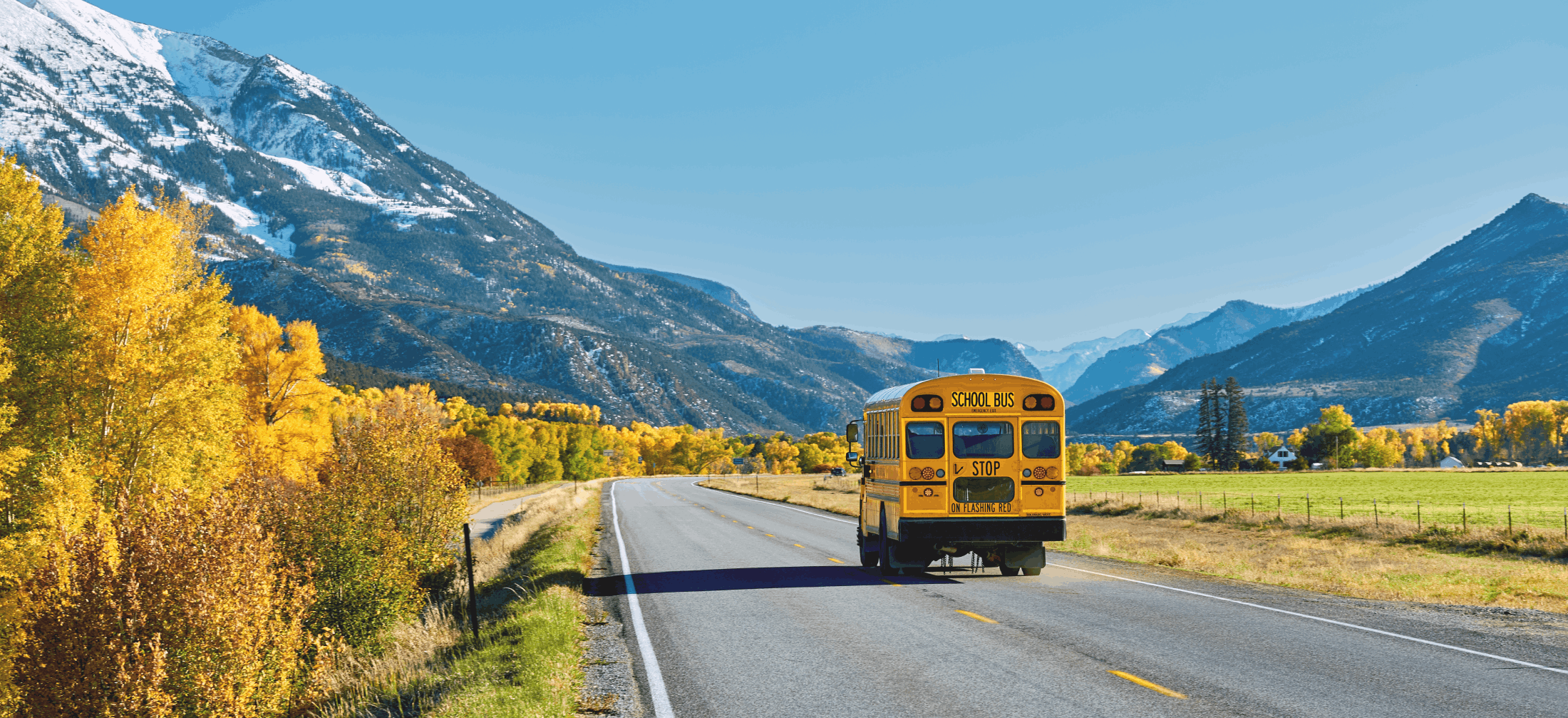 school bus on remote highway with mountains in background