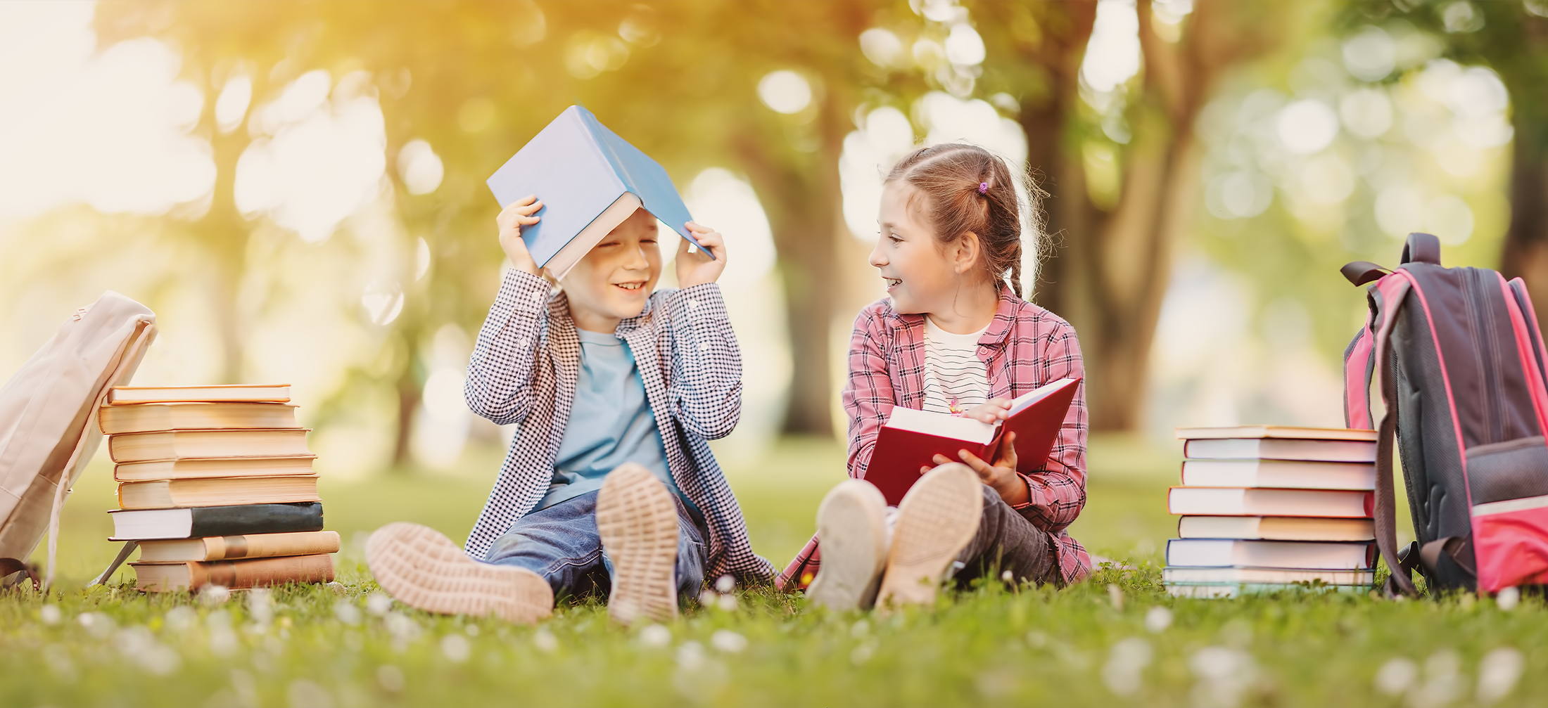 Boy and girl sitting on the meadow with books in their hands. Literacy image